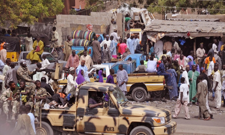 Image: Nigerian soldiers, left, pass on the back of a armed truck as they patrol Maiduguri