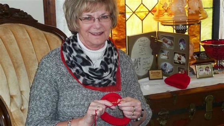 Sue Hipple knitting red caps for heart health awareness.