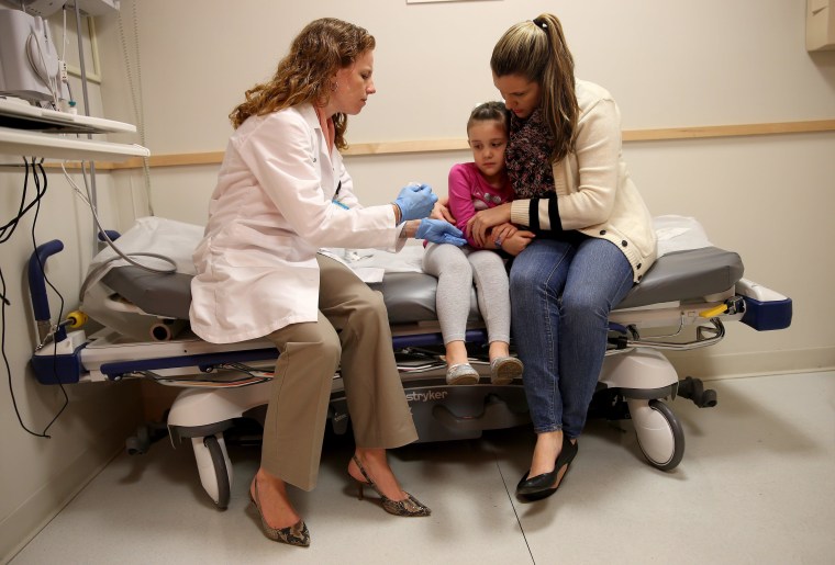 MIAMI, FL - JANUARY 28:  Miami Children's Hospital pediatrician Dr. Amanda Porro, M.D prepares to administer a measles vaccination to Sophie Barquin,4, as her mother Gabrielle Barquin holds her during a visit to the Miami Children's Hospital on January 28, 2015 in Miami, Florida. A recent outbreak of measles has some doctors encouraging vaccination as the best way to prevent measles and its spread.  (Photo by Joe Raedle/Getty Images)