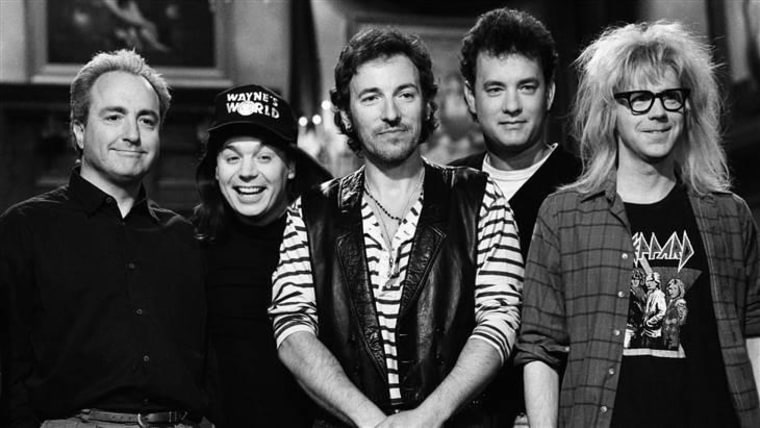 Lorne Michaels, with cast members Mike Meyers, musical guest Bruce Springsteen, host Tom Hanks, and cast member Dana Carvey on set in 1992.
