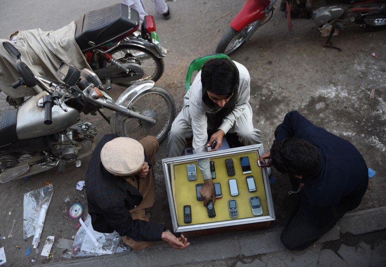 Image: A Pakistani mobile vendor sits with customers at his roadside stall