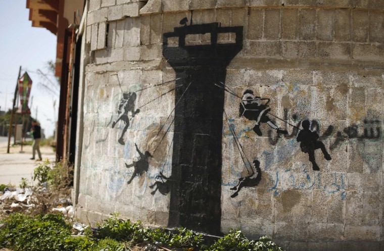 Image: A mural, presumably painted by British street artist Banksy, is seen on a wall in Biet Hanoun