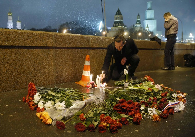 Image: A man places a lit candle at the place where Boris Nemtsov was shot dead near the Kremlin in central Moscow