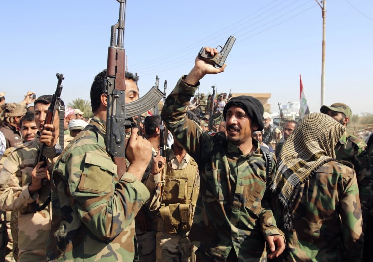 Image: Iraqi security forces and Shi'ite fighters chant slogans as they gather at Udhaim dam