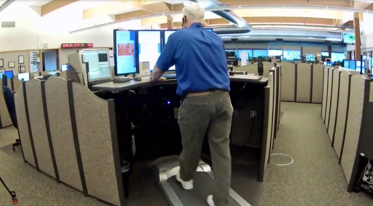 A 911 dispatcher walks on a treadmill while working in Beaverton, Ore.