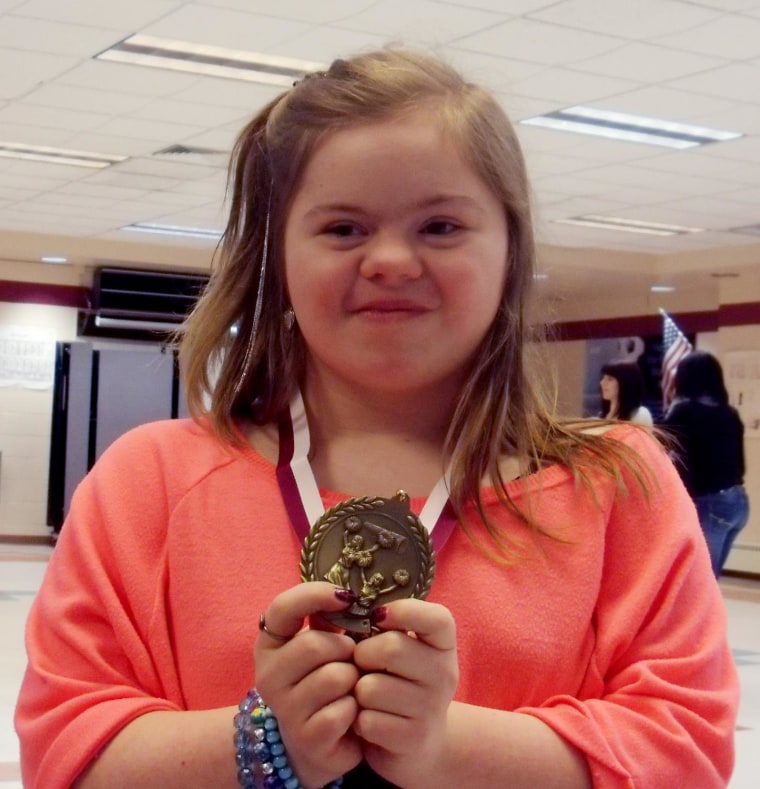 Desiree, holding up a medal she received at a cheerleader banquet.