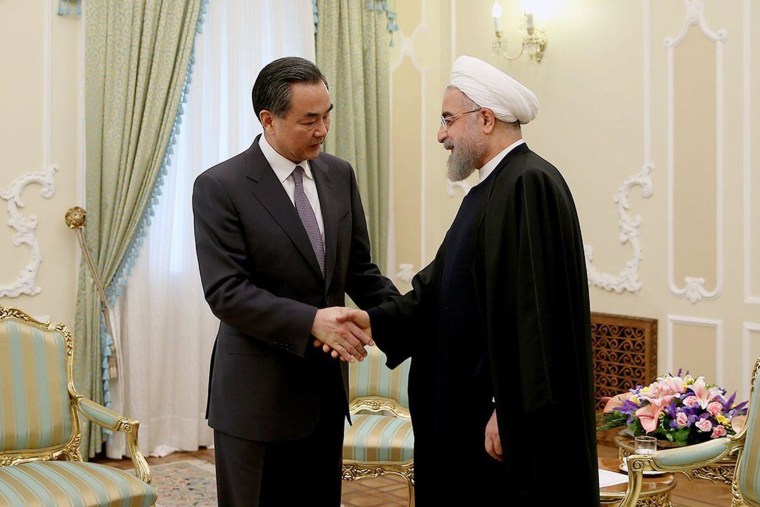 Image: Iranian President Hassan Rouhani shakes hands with Chinese Foreign Minister Wang Yi