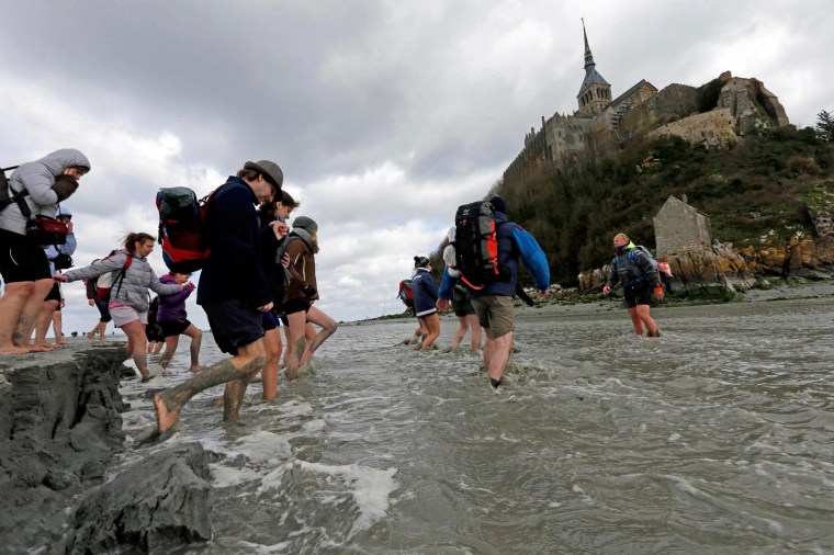 Image: Sebastien Daligault, a guide at the Bay Saint-Michel, stands knee-deep in water during a walking tour around the Mont Saint-Michel off France's Normandy coast
