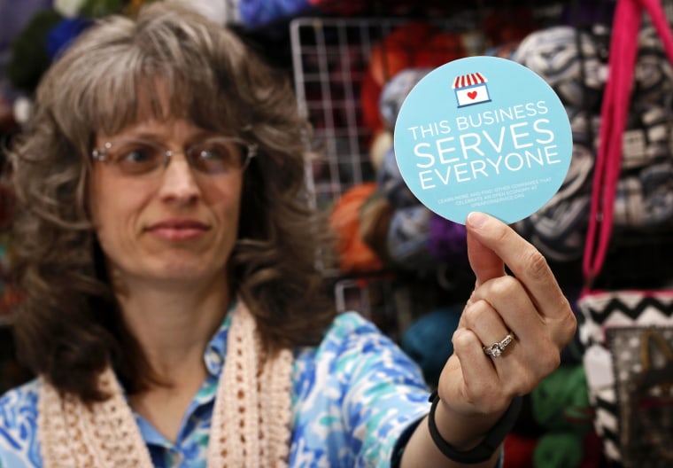 Image: Business owner holds sticker to place outside her shop in Lafayette, Indiana