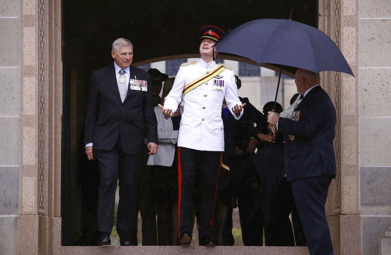 Britain's Prince Harry laughs as he looks up at the rain as Australia's Governor General Peter Cosgrove holds an umbrella for him.