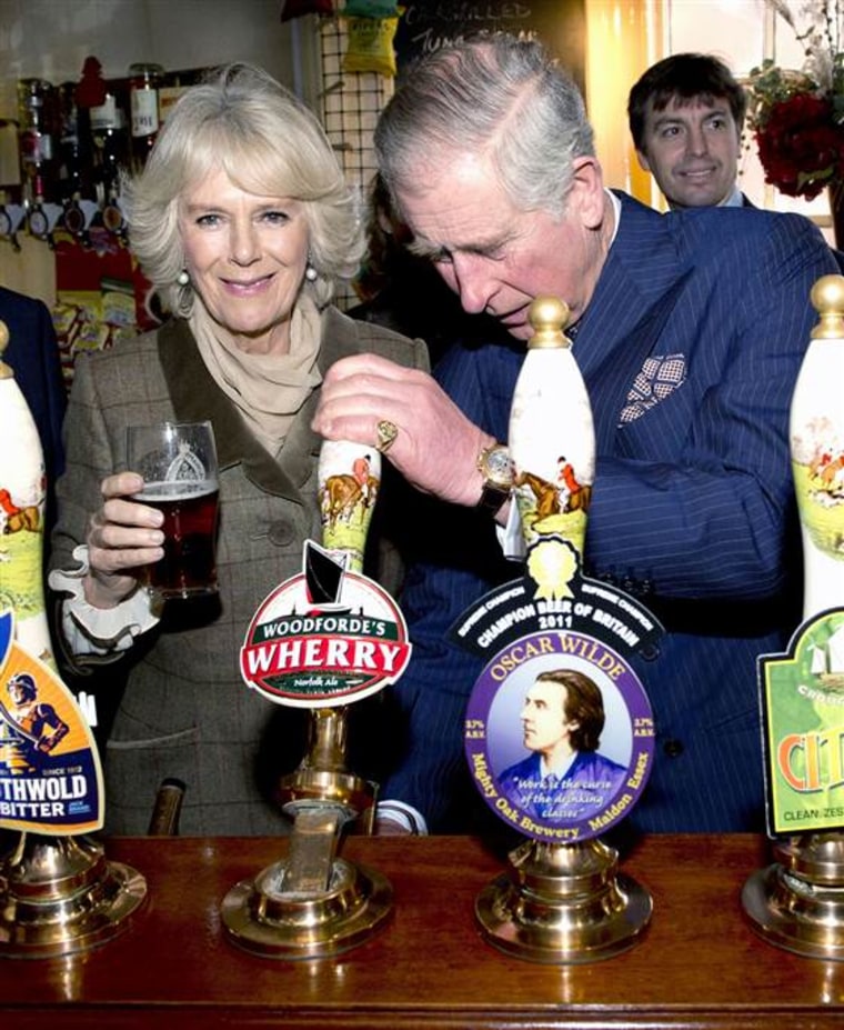 Britain's Prince Charles, The Prince of Wales, (Foreground-R) pulls a pint of draught beer as Camilla, The Duchess of Cornwall (L) looks on during a v...