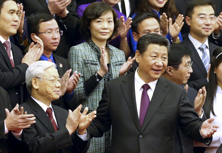 Image: China's President Xi gestures to Vietnam's Communist Party General Secretary Nguyen as they pose for a group photo with Chinese and Vietnamese youths at the Great Hall of the People in Beijing