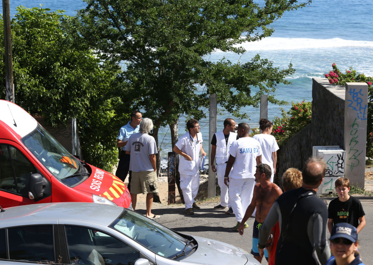 Image: Rescuers and onlookers stand near the beach after Sunday's shark attack