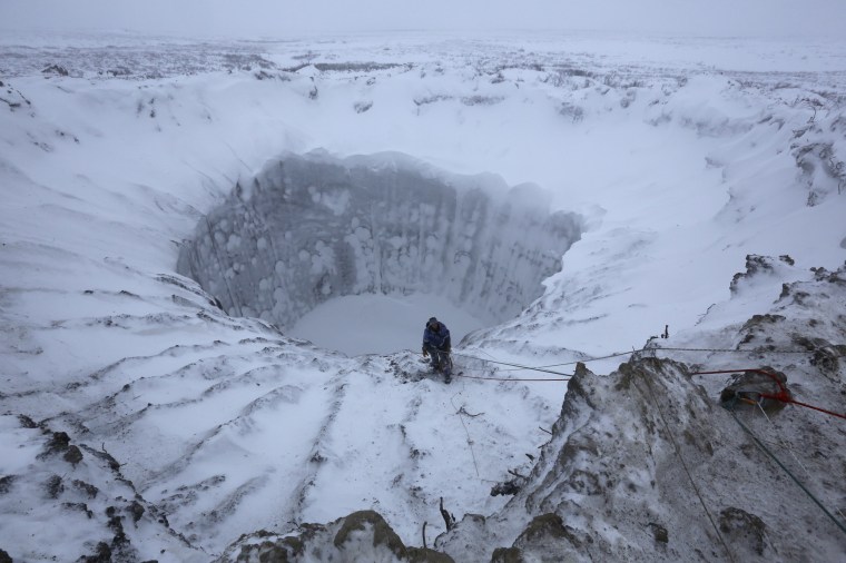 Image: A member of an expedition group stands on the edge of a crater on the Yamal Peninsula in 2014