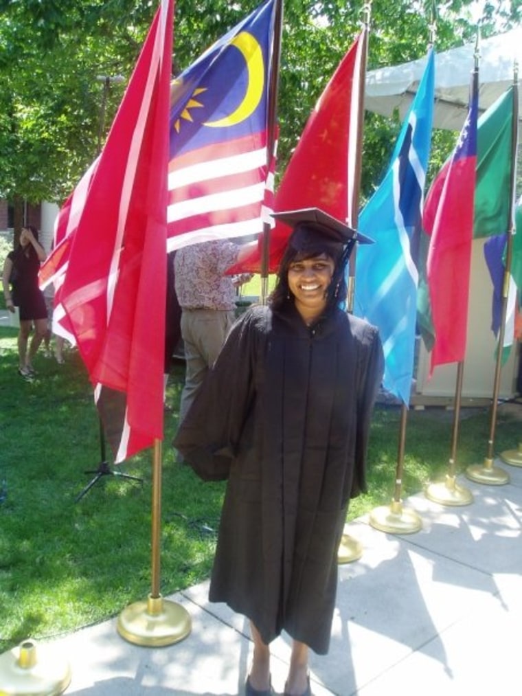 Dashini stands in front of the Malaysian flag after delivering the commencement address at Carleton College.