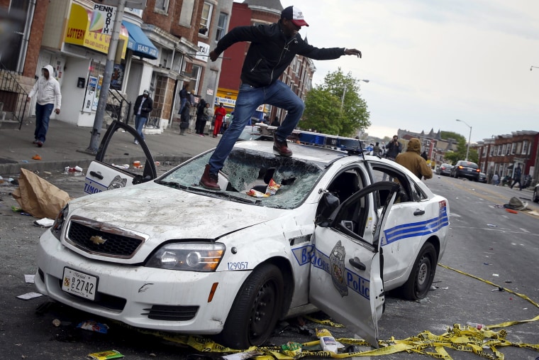 Image: Demonstrators jump on a damaged Baltimore police department vehicle during clashes in Baltimore
