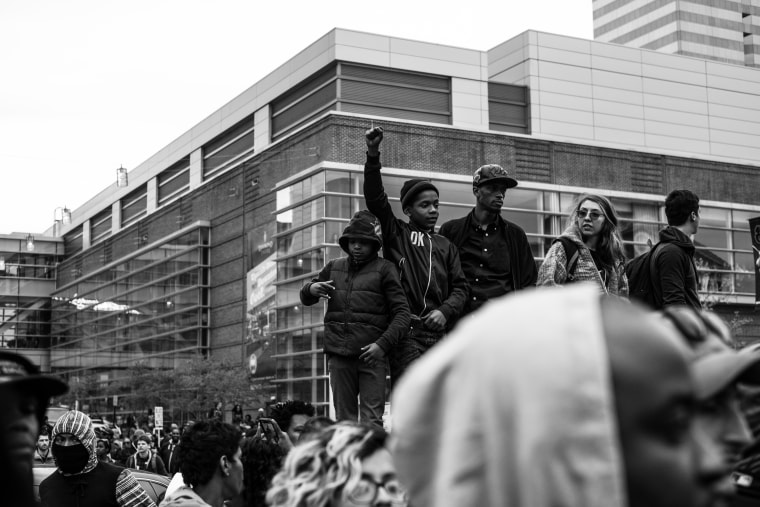 Protestors stand on an elevated surface in Baltimore during a Freddie Gray protest.