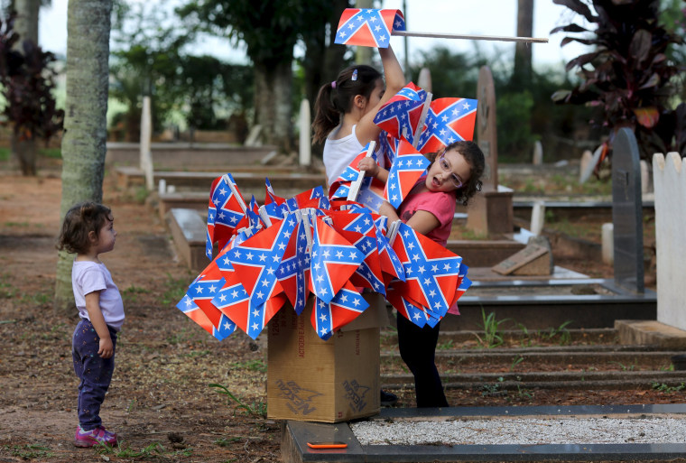 Image: Descendants of American Southerners play with confederate flags in a cemetery in Santa Barbara D'Oeste, Brazil