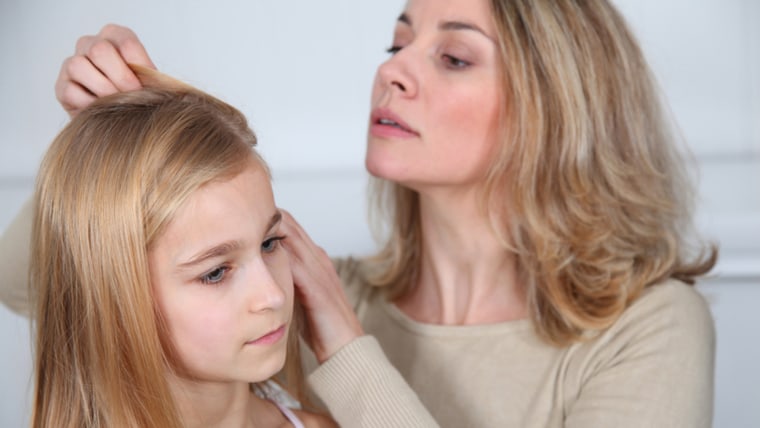 Mother treating daughter's hair against lice