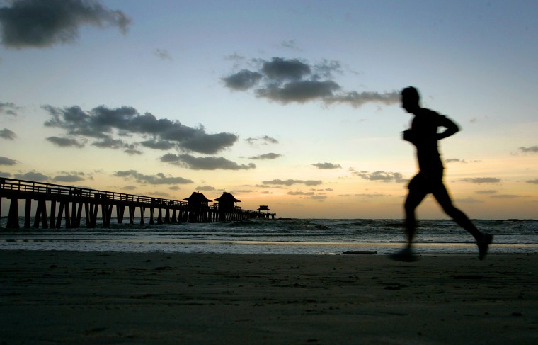 Image: A man runs along the beach near Naples Pier