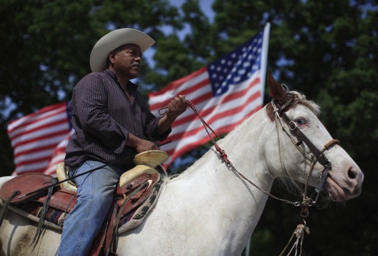 Image: A cowboy rides a horse through town as he watches a Cinco de Mayo celebration in Beardstown, Illinois