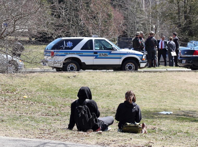 University of Rhode Island students, foreground, watch as State police and local police stand outside Chafee Hall, background, on the campus after the school ordered a lockdown of the campus in South Kingstown, R.I., Thursday, April 4, 2013.