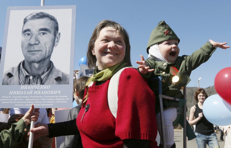 Image: Woman with child holds picture of World War Two soldier as she takes part in Immortal Regiment march during Victory Day celebrations in Divnogorsk