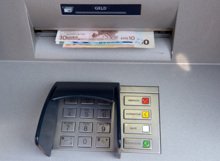 Bank notes are withdrawn at ATM in Berlin.