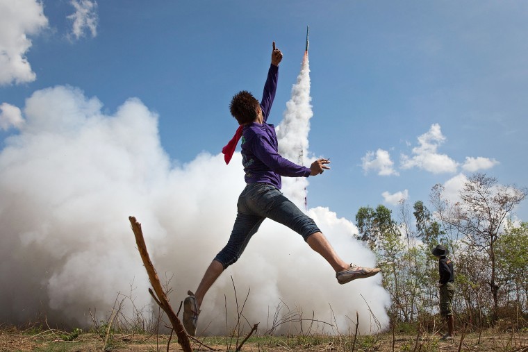 Image: A young Thai man jumps in the air and cheers as his rocket takes off