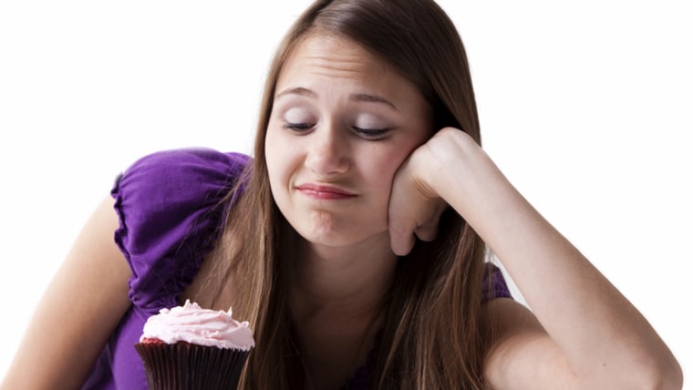 Woman with a sweet tooth resisting a cupcake