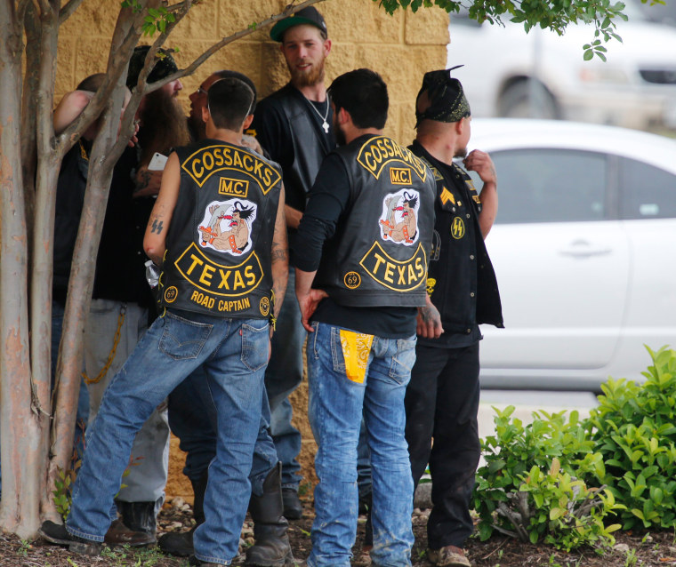 Image: Bikers congregate against a wall while authorities investigate a Twin Peaks restaurant