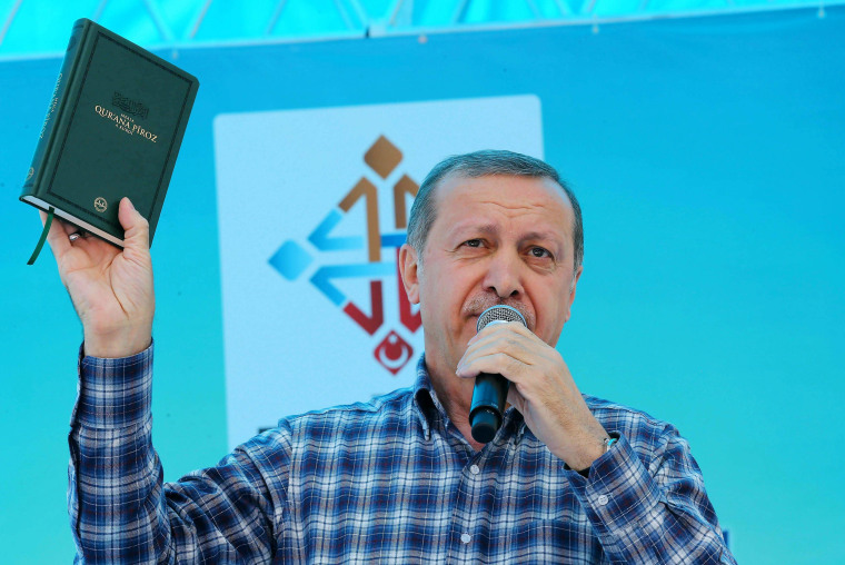 Image: Turkish President Recep Tayyip Erdogan holds a Quran during a political rally on May 2