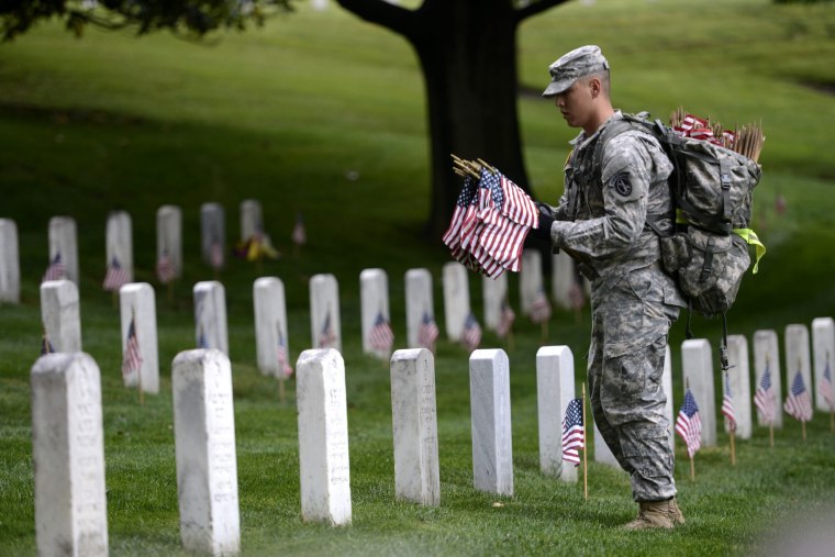 Image: The Old Guard places an American flag at headstones in Arlington National Cemetery