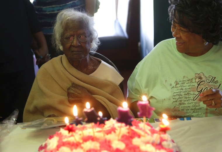 Image: Jeralean Talley, the world's oldest-known living person, looks at the candles on her cake while family and friends sing