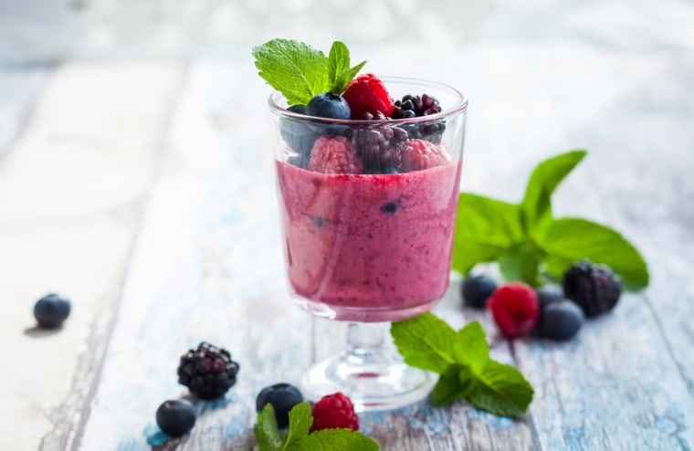 Raspberry and blueberry smoothie garnished with fresh berries in glass.