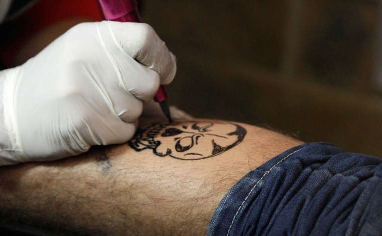 Image: Mohammed Abass, 28, draws a tattoo of a skull on Saad Saif's leg, 25, in Baghdad, Iraq