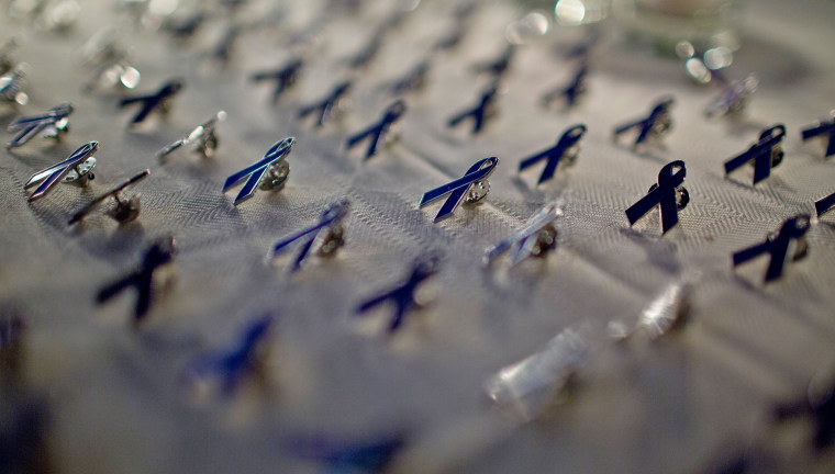 Purple ribbon pins are displayed for a domestic violence awareness candlelight vigil.