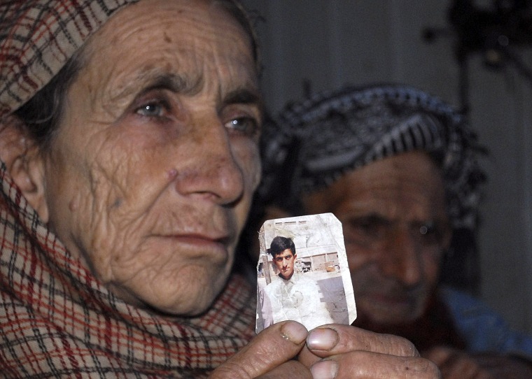 Image: Makhni Begum holds a photograph of her son Shafqat Hussain
