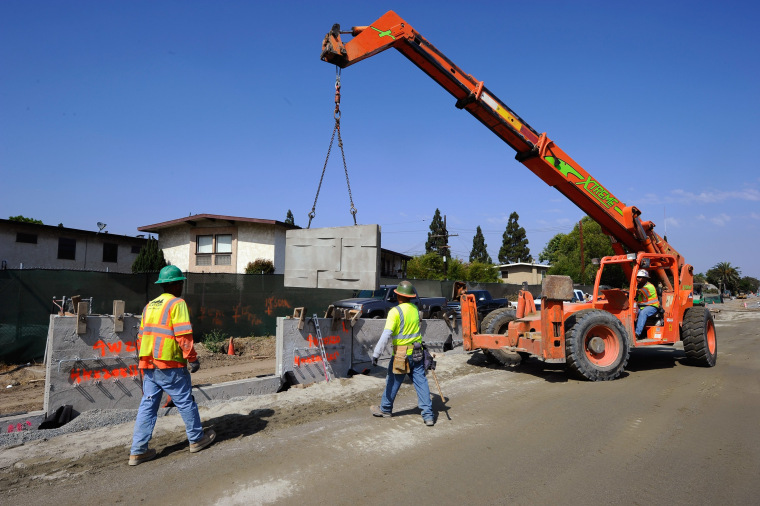 Image: Construction workers move a piece of concrete wall