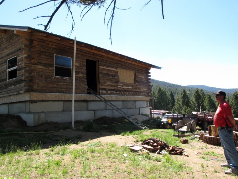 Image: Detective Steve Barclay stands in front of a fire-damaged cabin in the Beaverhead-Deerlodge National Forest outside Deer Lodge, Mont., on Monday, June 8, 2015, where a Montana man shot and killed his wife and three children Sunday morning