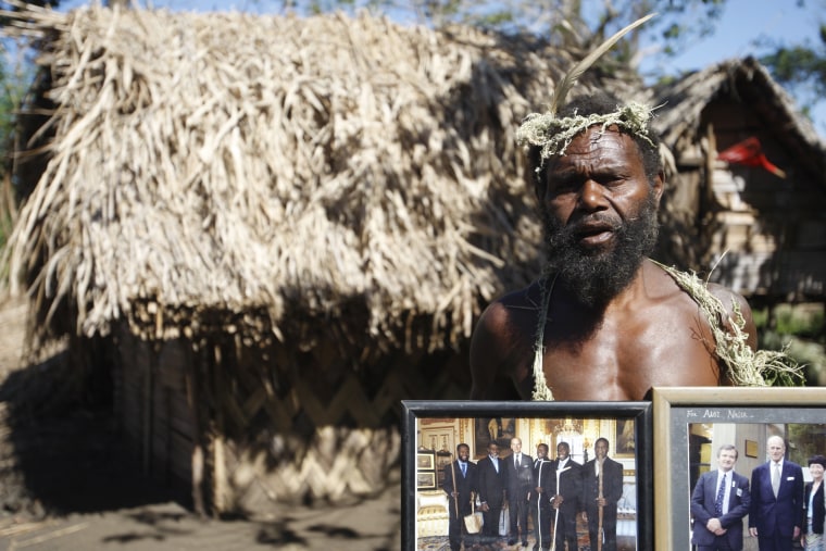 Image: Albi Nagia poses with photographs of Prince Philip in Yakel, Tanna island, Vanuatu.