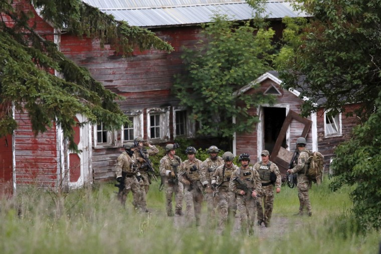Image: Police officers search a property near the Clinton Correctional Facility in Dannemora