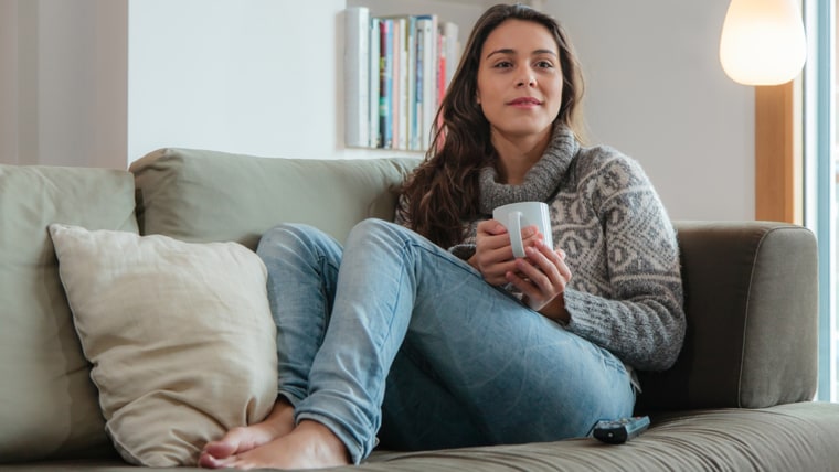 Young woman watching tv home in sofa