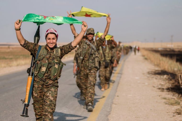 Image: Kurdish fighters gesture while carrying their parties' flags in Tel Abyad of Raqqa governorate after they said they took control of the area