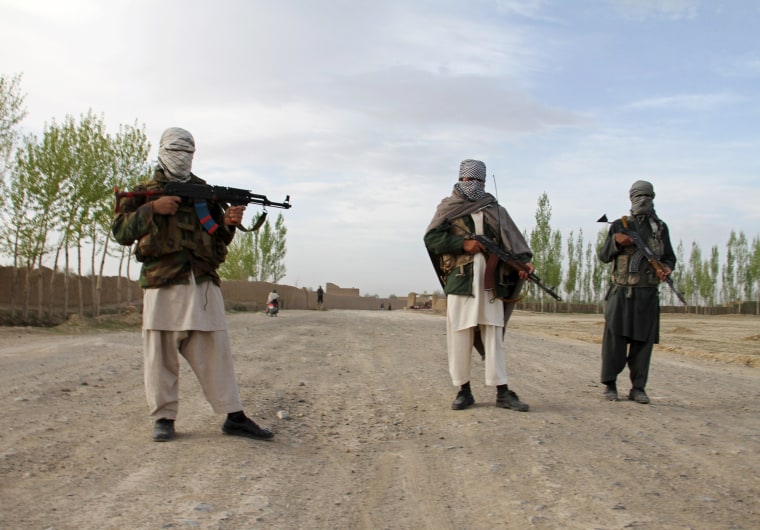 Image: Members of the Taliban stand at the site of the execution of three men in Ghazni Province
