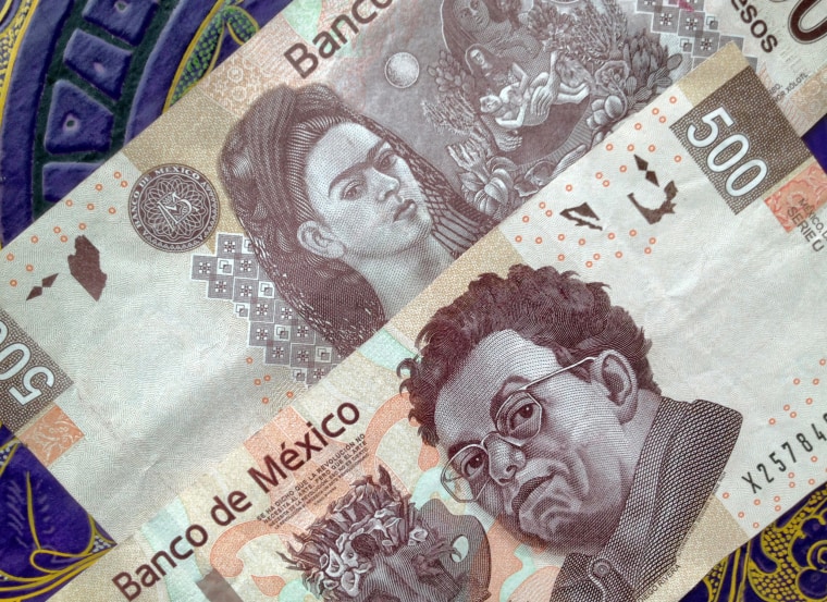 500 Mexican pesos notes on a table with traditional Mexican ornament. The note has the portrait of the painter Diego Riviera on one side and Frida Kahlo on the other.