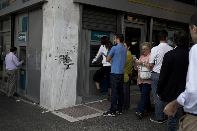 Image: People line up at an ATM outside a branch of the National Bank, in central Athens, on Friday.