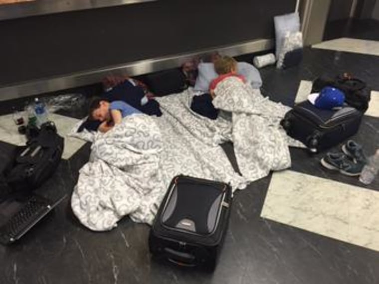 Image: Evan (L) and Erick Sliter, aged 8 and 10, sleeping on the floor of Belfast International Airport, Northern Ireland, early Sunday.