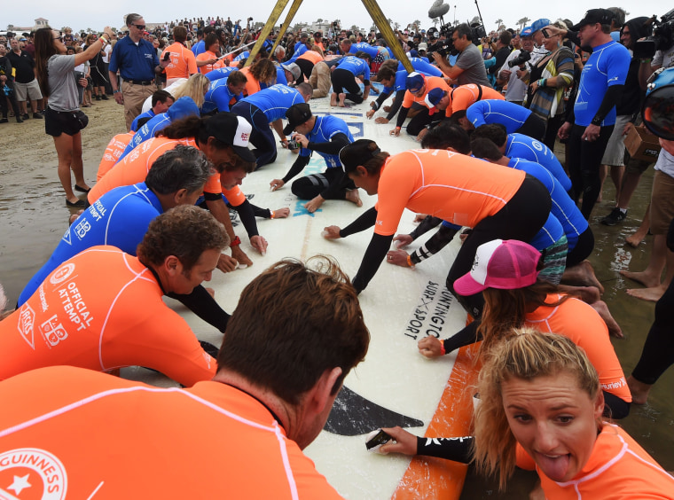 Image: A surfboard is waxed as sixty six surfers from Huntington Beach prepare to break the 'Guinness Book of Records' record