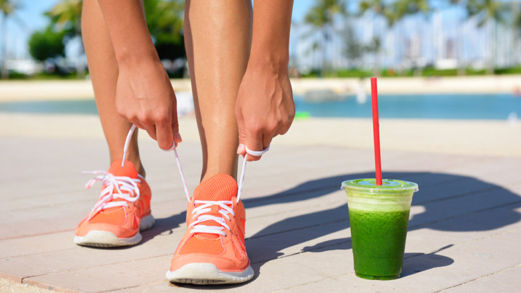 Woman with green juice tying sneakers